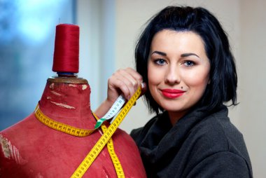 Seamstress with red old mannequin and measuring tape in her work clipart