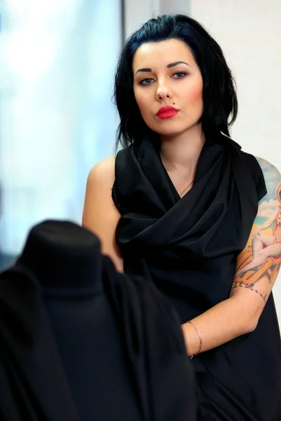 Etalagepop omwikkeld met zwarte doek met meisje met tatoeage achter — Stockfoto