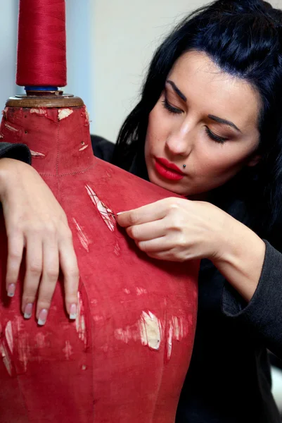 Näherin repariert rote alte Schaufensterpuppe mit ihren Händen in ihren Werken — Stockfoto