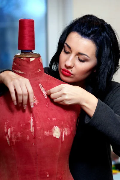 Seamstress repairs red old mannequin with her hands in her works — Stock Photo, Image