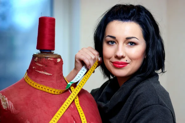 Seamstress with red old mannequin and measuring tape in her work — Stock Photo, Image