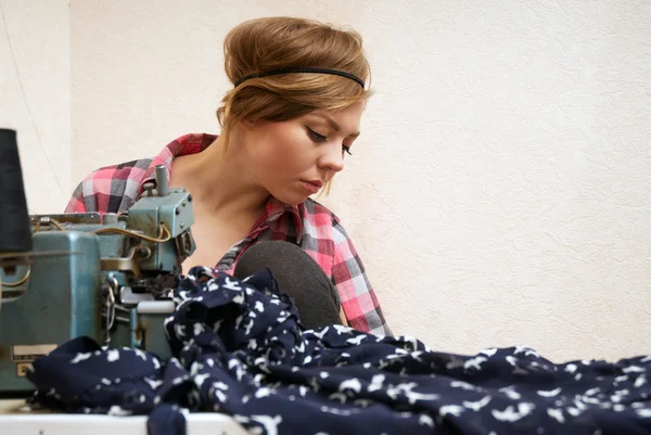 Vrouw naaister poseren in de buurt van naaimachine — Stockfoto