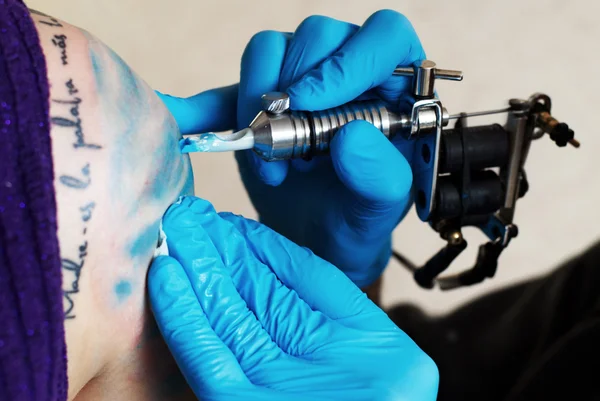 Handen van tatoeëerder creat een tatoeage — Stockfoto