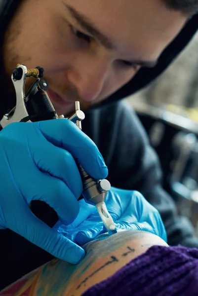 Bearded Caucasian tattooist creates a tattoo on a woman's should — Stock Photo, Image