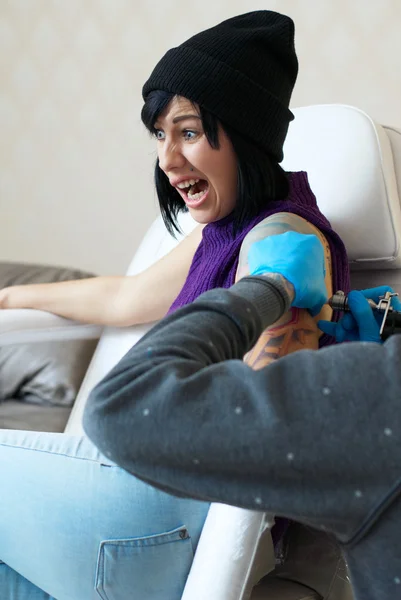 Emociones de una chica mientras hace un tatuaje — Foto de Stock