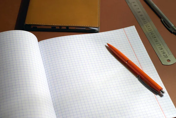 New square lined exercise book with orange pen — Stock Photo, Image