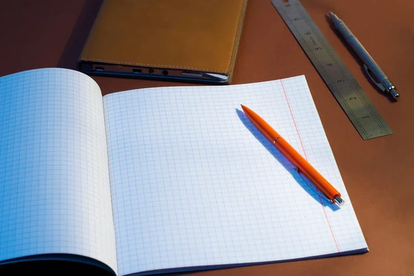 New square lined exercise book with orange pen — Stock Photo, Image