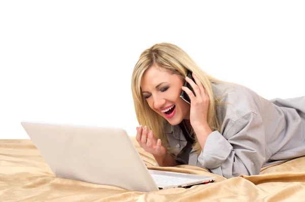 Блондинка работает с ноутбуком на кровати — стоковое фото
