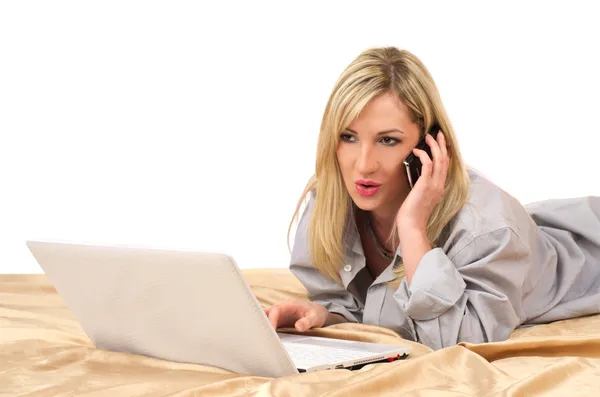 Блондинка работает с ноутбуком на кровати — стоковое фото
