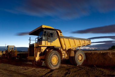 Huge auto-dump yellow mining truck night shot and excavator clipart