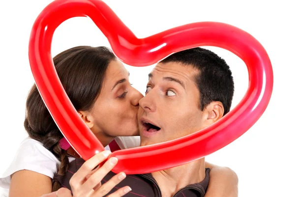 Молодая пара целуется через воздушный шар сердце сюрприз изолирован — стоковое фото