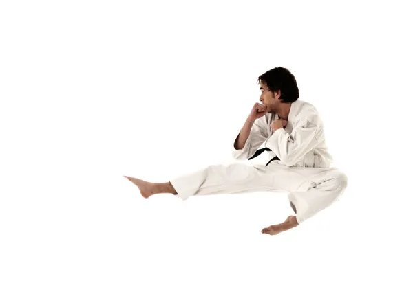 Karate Flying Kick junger männlicher Kämpfer isoliert auf weißem Hintergrund. Stockbild