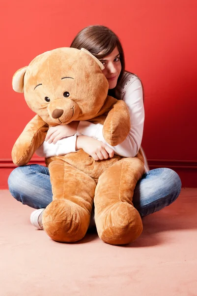 stock image Young woman embracing teddy bear sitting on floor