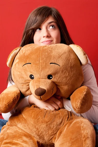 Junge Frau umarmt Teddybär und schaut aus nächster Nähe auf Stockbild