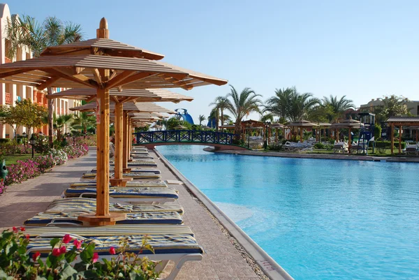 在酒店的游泳池在遮阳伞下的板床。埃及 — 图库照片
