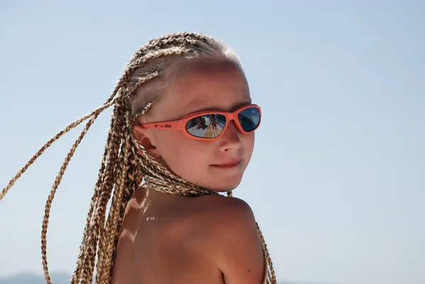 stock image The girl in pink glasses with the African plaits. A portrait