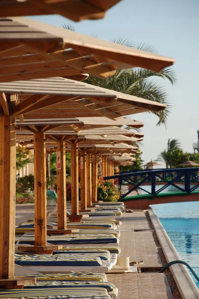 Plank beds under umbrellas at pool in hotel. Egypt — Stock Photo, Image