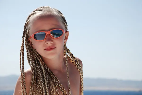 stock image The girl in pink glasses with the African plaits. A portrait