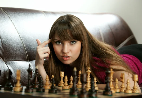 Девушка с шахматами на диване — стоковое фото