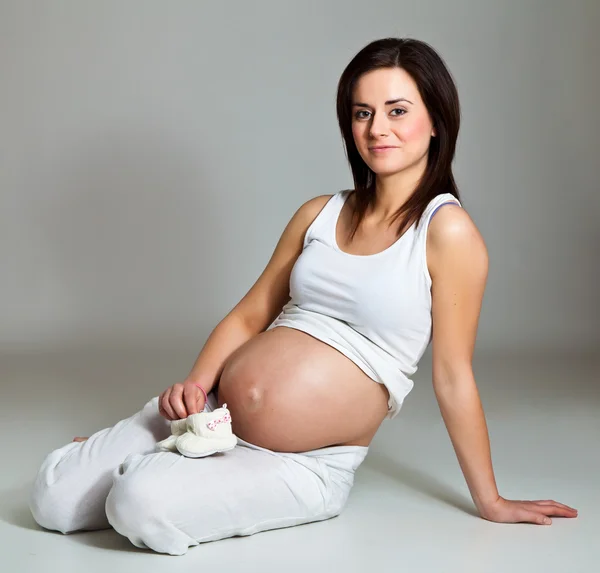 Morena grávida em fundo neutro — Fotografia de Stock