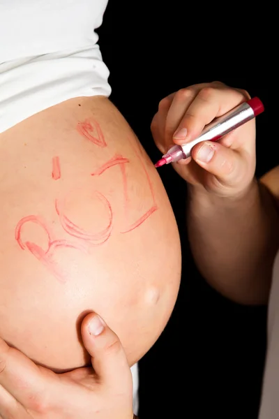 Těhotné břicho s rukama na černém pozadí — Stock fotografie