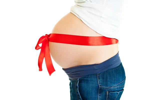 Brunetka kobieta w ciąży z czerwoną wstążką na białym tle — Zdjęcie stockowe