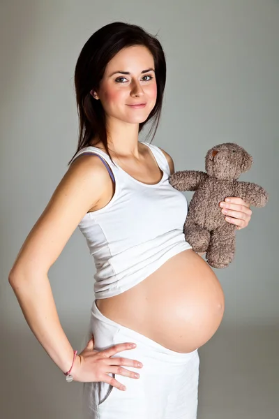 Pregnant brunette on neutral background — Stock Photo, Image