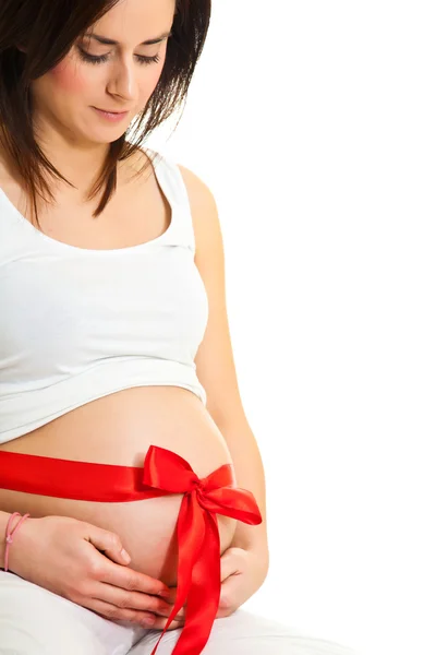 Esmer hamile kadın üzerinde beyaz izole kırmızı kurdele ile — Stok fotoğraf