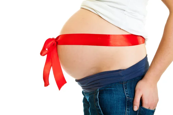 Bruneta těhotná žena s červenou mašlí izolované na bílém — Stock fotografie