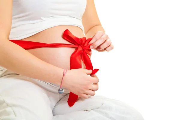 Brunette pregnant woman with red ribbon isolated on white — Stock Photo, Image