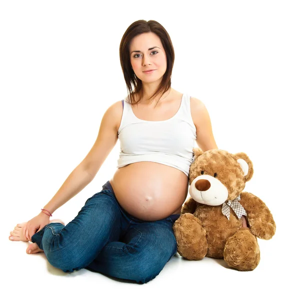 Morena embarazada con osito de peluche aislado en blanco — Foto de Stock