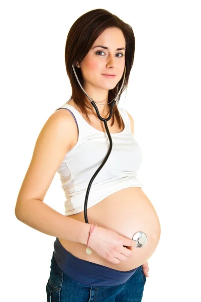 Mujer embarazada examinando el vientre con estetoscopio aislado — Foto de Stock