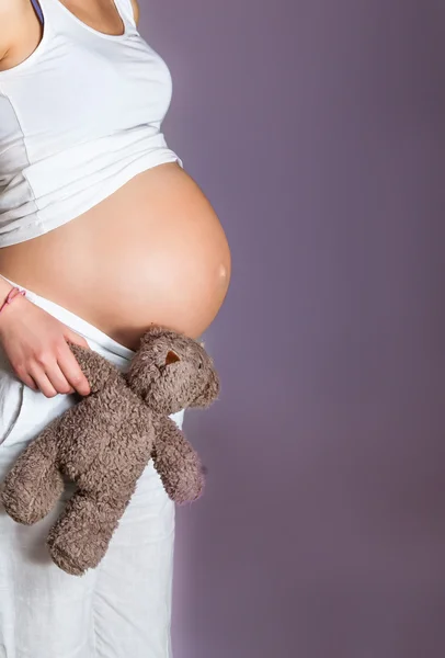 Беременная женщина на фиолетовом фоне — стоковое фото