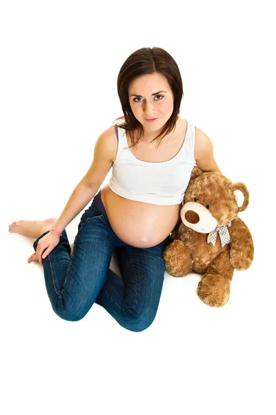 Brünette schwangere Frau mit Teddybär isoliert auf weiß — Stockfoto