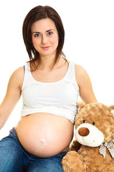 Μελαχρινή γυναίκα έγκυος με αρκουδάκι που απομονώνονται σε λευκό — Φωτογραφία Αρχείου