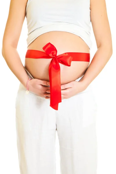 Brunetka kobieta w ciąży z czerwoną wstążką na białym tle — Zdjęcie stockowe