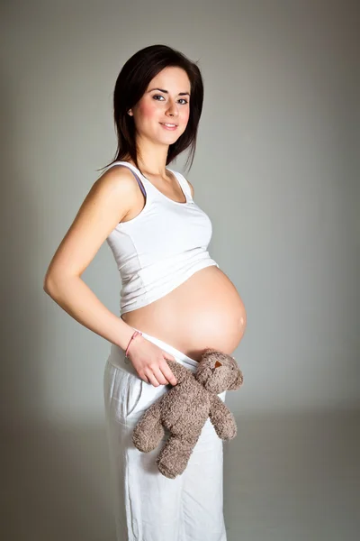 Těhotná bruneta na neutrální pozadí — Stock fotografie