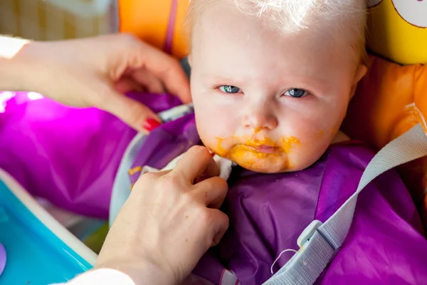 Ongelukkig baby girl leren om vast voedsel te eten — Stockfoto