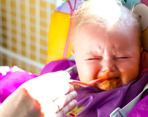 Olycklig spädbarn flicka lära sig att äta fast föda — Stockfoto