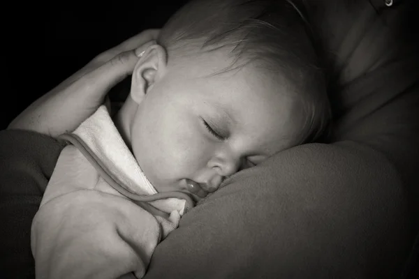 Sover barnet i mödrar armar — Stockfoto