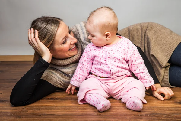 Infant baby girl with mother on wooden floor — Stock Photo, Image