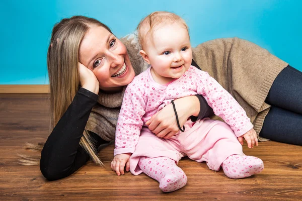 Spädbarn flicka med mamma på trägolv — Stockfoto