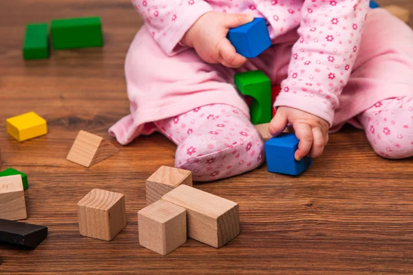 Infant girl playing in room on wooden floor — Stock Photo, Image