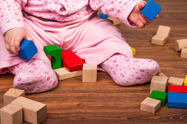 Infant girl playing in room on wooden floor — Stock Photo, Image