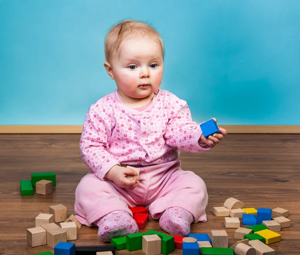 Infant girl playing in room on wooden floor — Stock Photo, Image