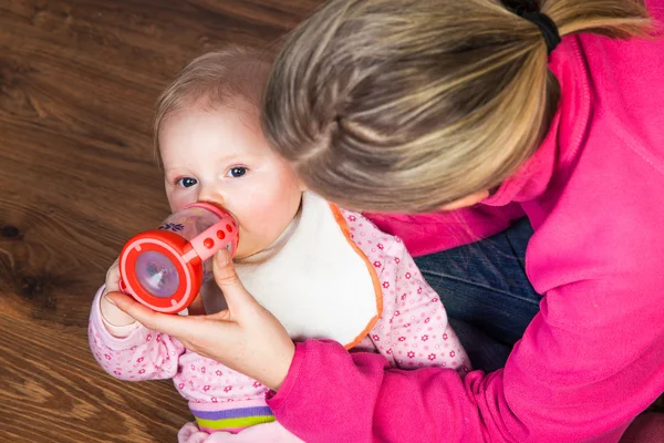 Mãe alimentando menina infantil com uma garrafa de chá — Fotografia de Stock