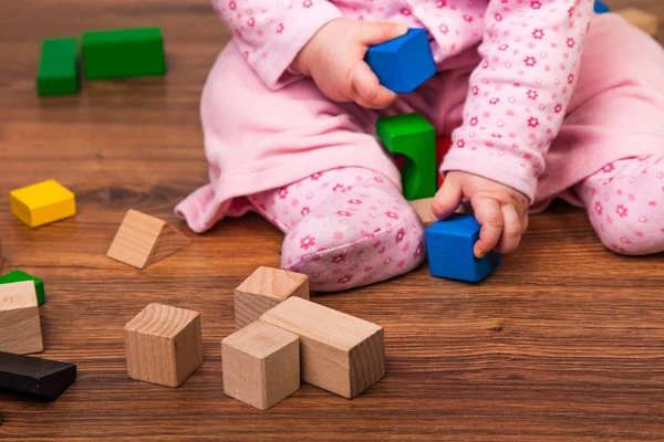 Infant girl playing in room on wooden floor Royalty Free Stock Photos