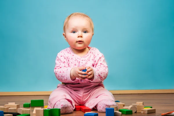 Infant girl playing in room on wooden floor Stock Image