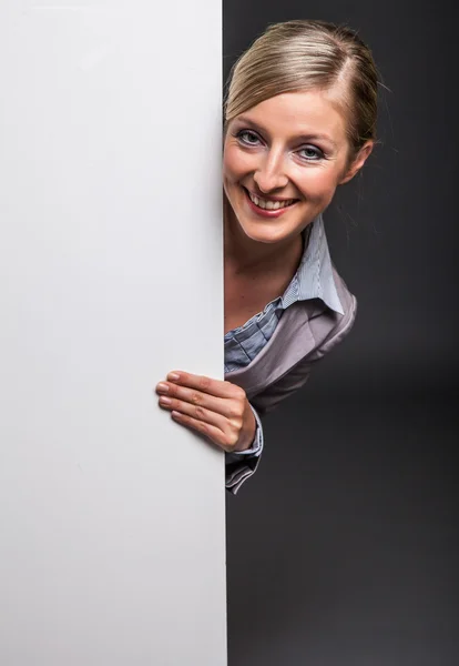 Woman behind white banner on dark gray background — Stock Photo, Image