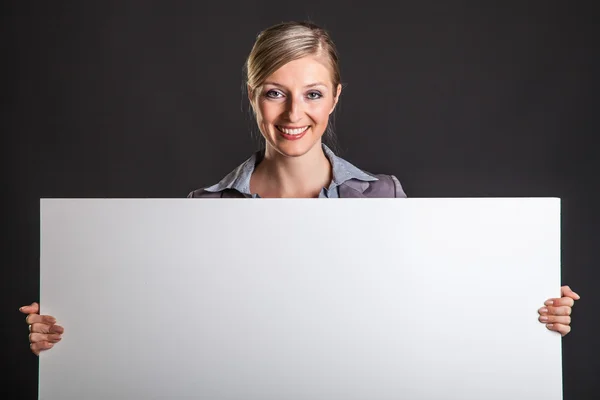 Woman behind white banner on dark gray background Stock Picture